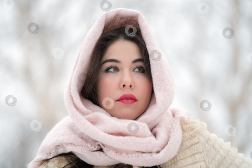 Скачать Портрет задумчивой молодой женщины-брюнетки в белой шубе и светло-розовом шарфе на голове, смотрящей в сторону фотосток Ozero