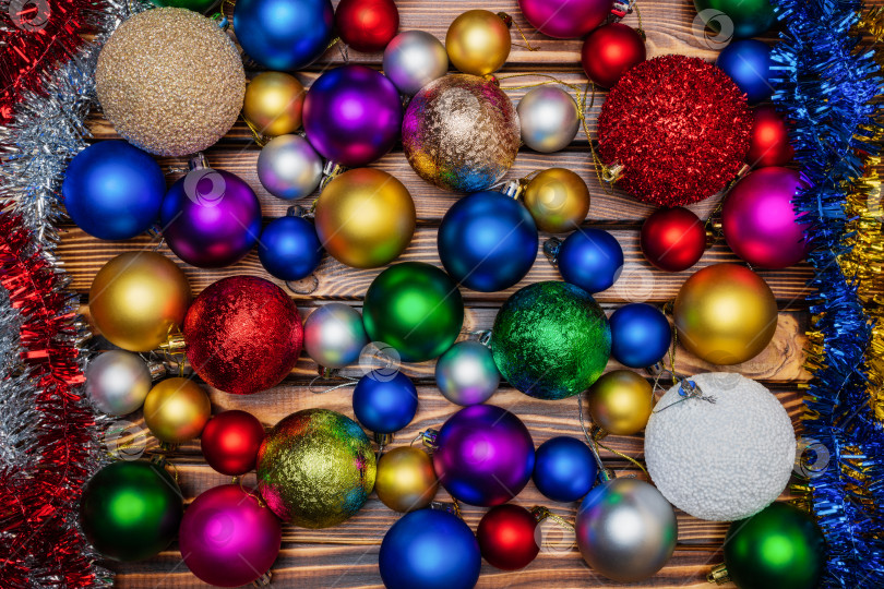 Скачать Разноцветные рождественские шары и мишура на фоне деревянного стола. Вид рождественского украшения крупным планом фотосток Ozero