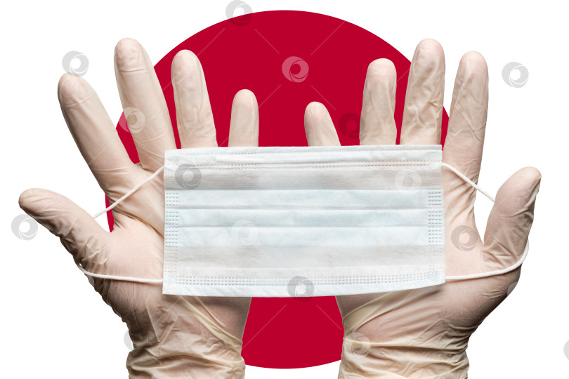 Скачать Медсестра держит респираторную маску двумя руками в белых перчатках на фоне флага Японии фотосток Ozero