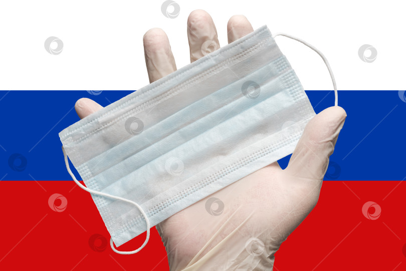 Скачать Врач держит в руке маску для лица в белой медицинской перчатке на фоне цветов флага России. Концепция страхования от пандемии коронавируса фотосток Ozero