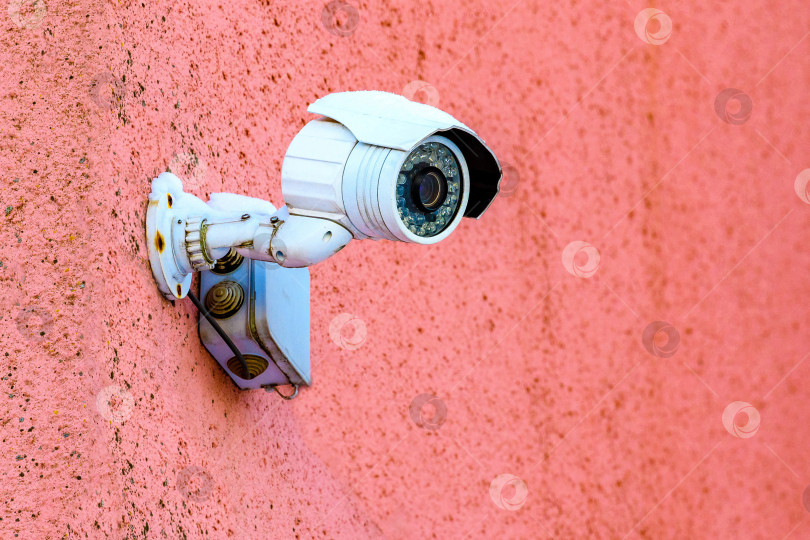 Скачать Камера видеонаблюдения: Камера видеонаблюдения установлена на красной стене для мониторинга условий дорожного движения на городской улице. Защита собственности и забота о безопасности. фотосток Ozero