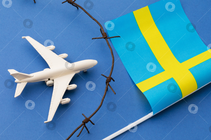 Скачать Игрушечный самолет, шведский флаг и колючая проволока на синем фоне, концепция нарушения воздушной границы Швеции фотосток Ozero