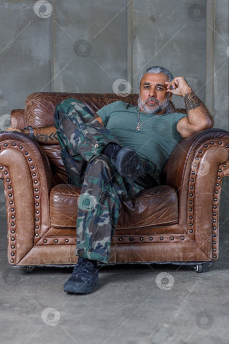 Скачать Солдат в камуфляже, солдат, сидящий в кресле.Зрелый мужчина-культурист в военной форме. фотосток Ozero
