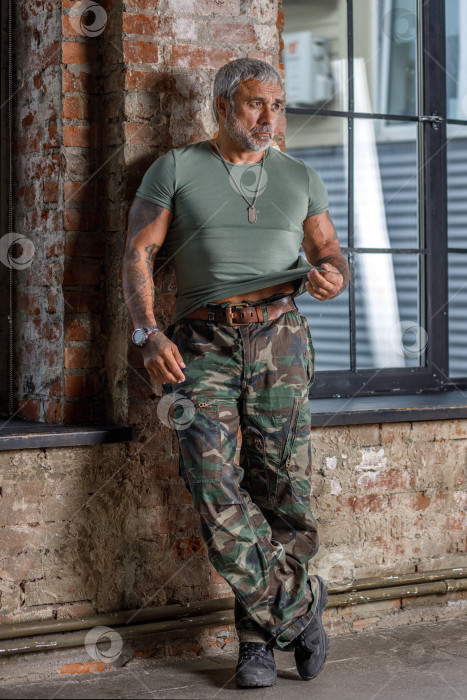 Скачать Солдат в камуфляже, солдат стоит у стены.Зрелый мужчина-культурист в военной форме. фотосток Ozero