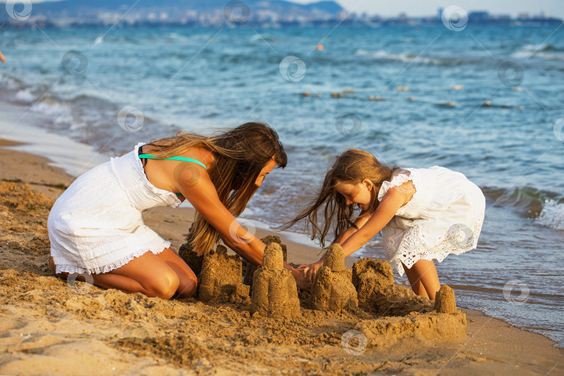 Скачать Мама и дочь строят замки из песка на пляже солнечным летним вечером фотосток Ozero