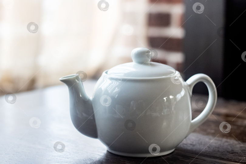 Скачать Белый чайник с чаем на деревянном столе фотосток Ozero