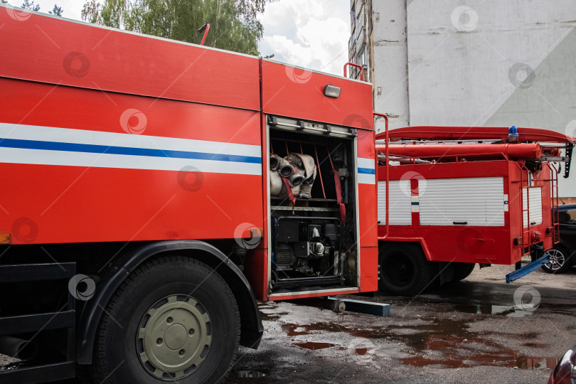 Скачать Две красные пожарные машины крупным планом возле дома фотосток Ozero