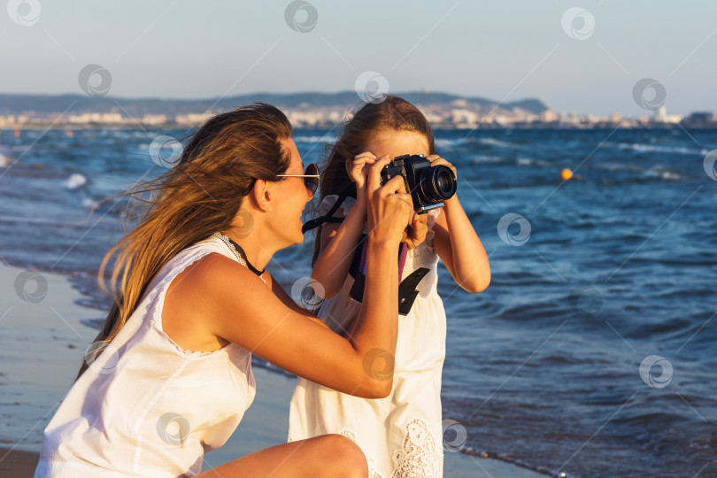 Скачать Мама и дочь фотографируются на пляже теплым летним вечером фотосток Ozero