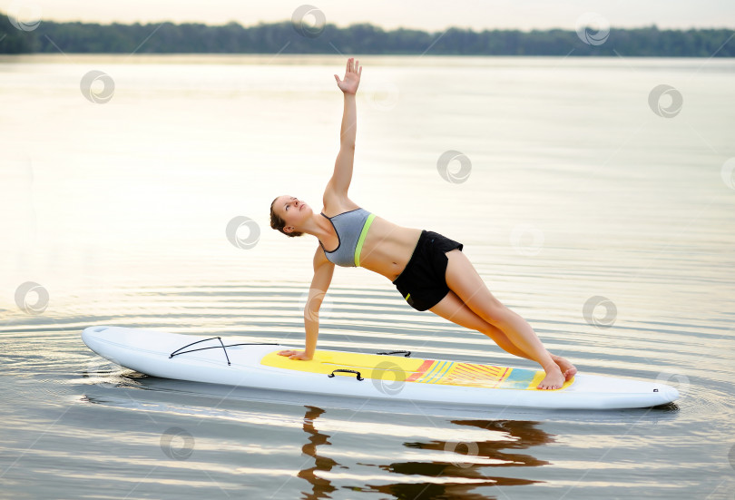 Скачать Спортивная женщина на гребной доске, практикующая позу боковой доски фотосток Ozero