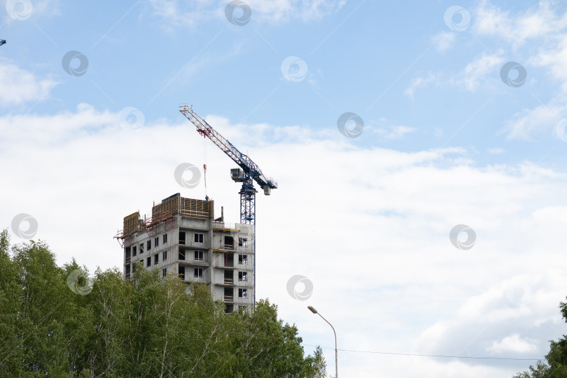 Скачать Вид на недостроенную стену дома. Строительный кран на фоне голубого неба. фотосток Ozero