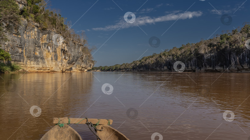 Скачать Деревянное каноэ плывет по спокойной красно-коричневой воде. фотосток Ozero