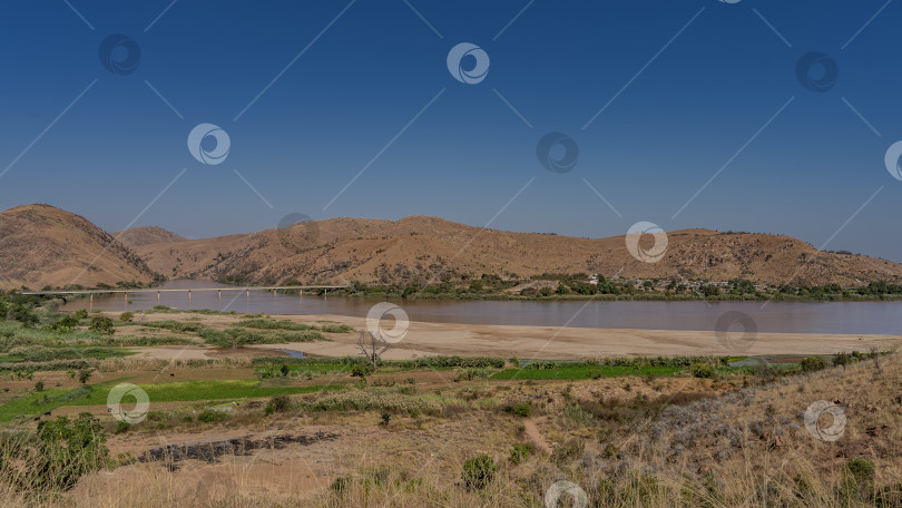 Скачать Спокойная красно-коричневая река течет между горными склонами фотосток Ozero