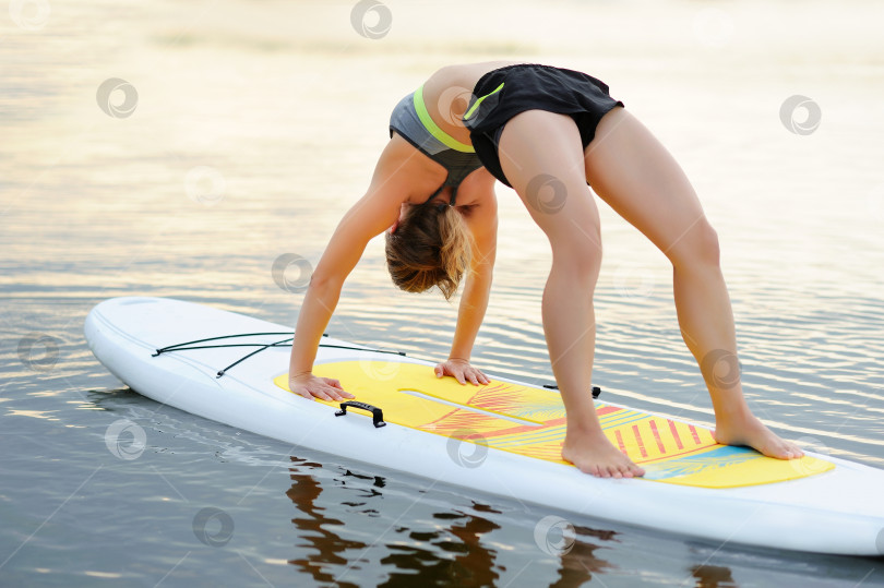 Скачать Женщина, практикующая позу бридж-йоги на доске для гребли фотосток Ozero