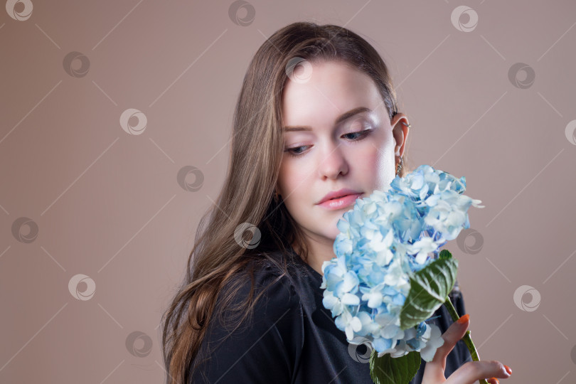 Скачать Нежная молодая женщина с цветком в руках. Голубая гортензия у лица. Прекрасная дама позирует с цветами. Запах летних цветов фотосток Ozero