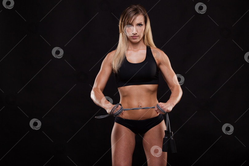 Скачать Красивая фитнес-женщина держит в руках скакалку. Спортивная девушка, демонстрирующая свое хорошо тренированное тело. изолированный на темном фоне с помощью copyspace фотосток Ozero