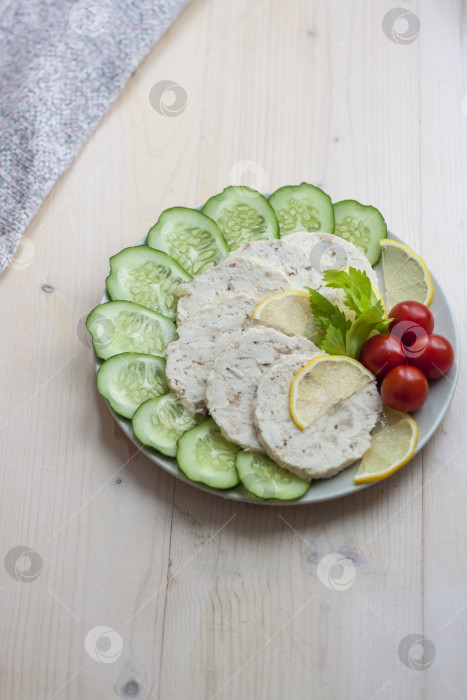 Скачать Мясо запеченной курицы нарезать ломтиками. Ломтики запеченного куриного мяса выкладывают на тарелку вместе с огурцом и помидорами черри. фотосток Ozero