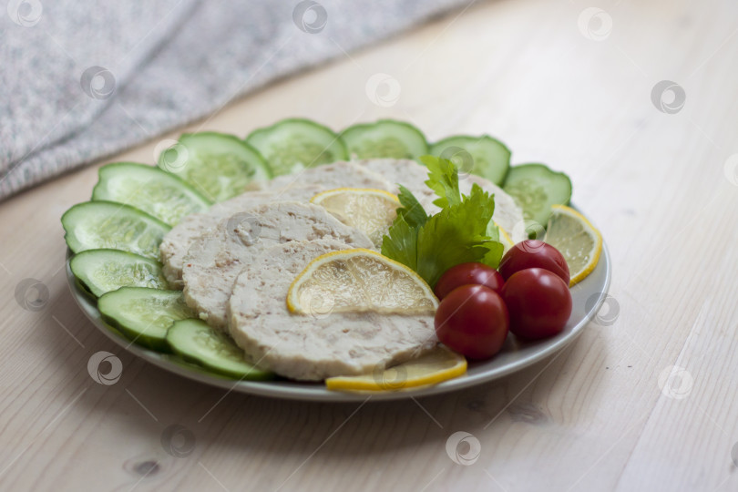 Скачать Мясо запеченной курицы нарезать ломтиками. Ломтики запеченного куриного мяса выкладывают на тарелку вместе с огурцом и помидорами черри. фотосток Ozero