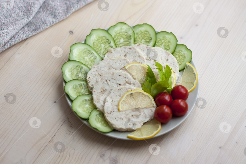 Скачать Мясо запеченной курицы нарезать ломтиками. Ломтики запеченного куриного мяса выкладывают на тарелку вместе с огурцом и помидорами черри. фотосток Ozero