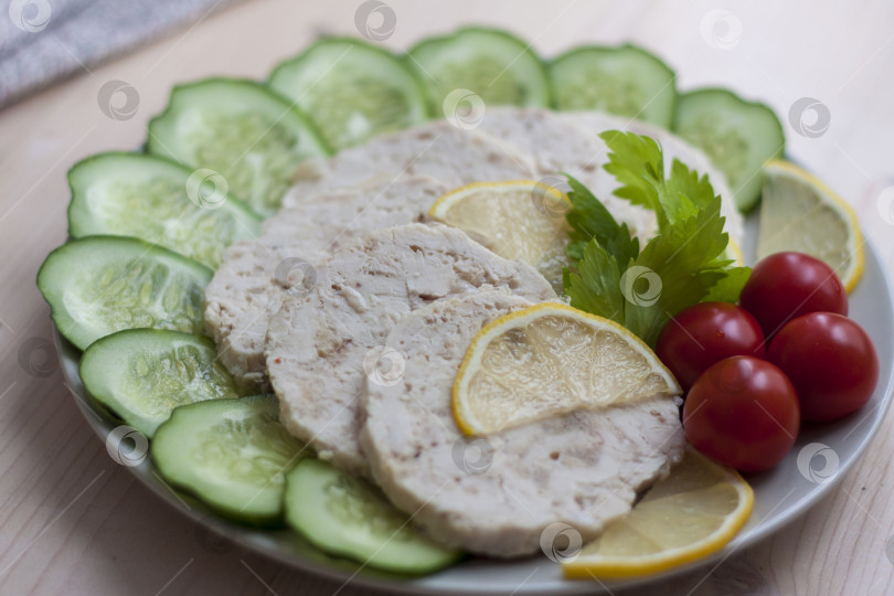 Скачать Мясо запеченной курицы нарезать ломтиками. Ломтики запеченного куриного мяса выкладывают на тарелку вместе с огурцом и помидорами черри. фотосток Ozero