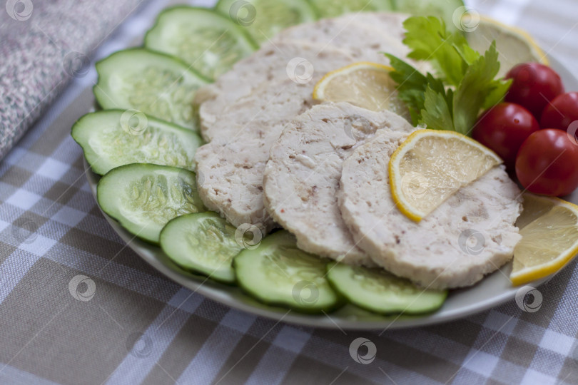 Скачать Мясо запеченной курицы нарезать ломтиками. Ломтики запеченного куриного мяса выкладывают на тарелку вместе с огурцом и помидорами черри. фотосток Ozero