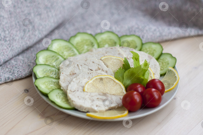 Скачать Мясо запеченной курицы нарежьте ломтиками. Ломтики запеченного куриного мяса выкладываем на тарелку вместе с огурцом и помидорами черри. фотосток Ozero