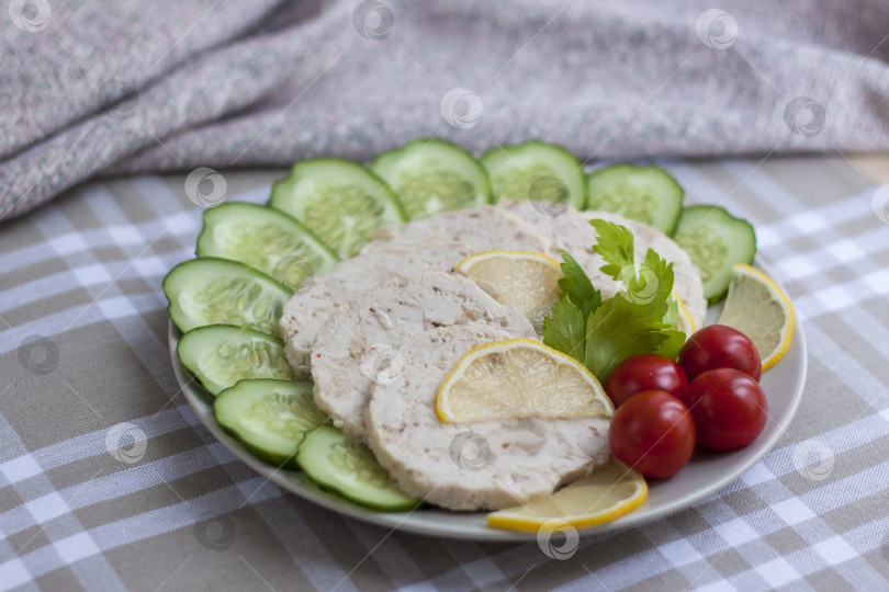 Скачать Мясо запеченной курицы нарезать ломтиками. Ломтики запеченного куриного мяса выкладывают на тарелку вместе с огурцом и помидорами черри. фотосток Ozero