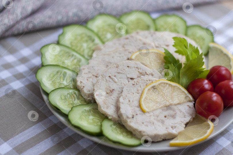 Скачать Мясо запеченной курицы нарезать ломтиками. Ломтики запеченного куриного мяса выкладывают на тарелку вместе с огурцом и помидорами черри. фотосток Ozero