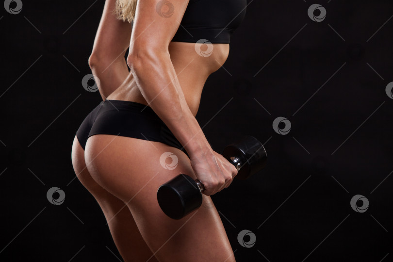 Скачать Крупным планом привлекательная спортивная женщина накачивает мышцы с помощью гантелей, вид сзади, изолированный на темном фоне с copyspace фотосток Ozero