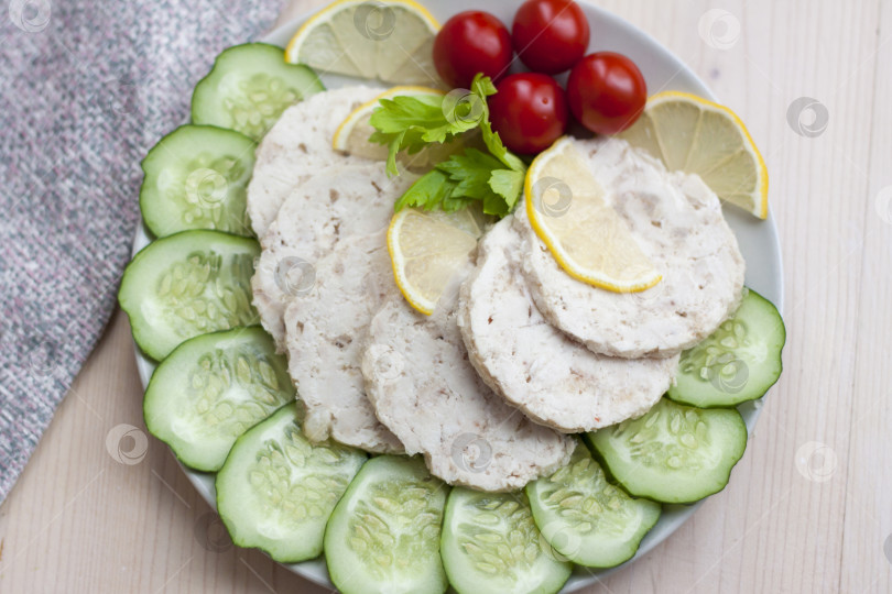 Скачать Мясо запеченной курицы нарезать ломтиками. Ломтики запеченного куриного мяса выкладывают на тарелку вместе с огурцом и помидорами черри. фотосток Ozero