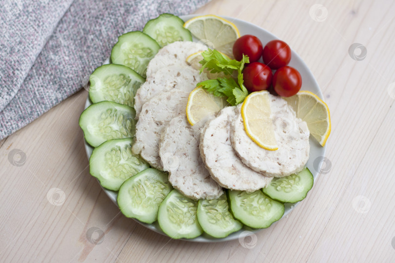 Скачать Мясо запеченной курицы нарежьте ломтиками. Ломтики запеченного куриного мяса выкладываем на тарелку вместе с огурцом и помидорами черри. фотосток Ozero