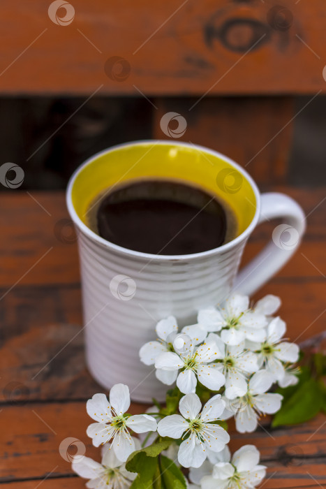 Скачать чашка кофе на темном, потертом деревянном столе в деревенском стиле. Композиция украшена веточкой с белыми цветами. Цветы вишневого дерева. Выборочный акцент. фотосток Ozero