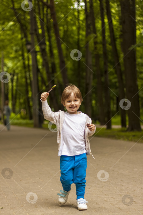 Скачать Милый маленький мальчик держит в руках большой круглый леденец на палочке. Радостные эмоции. Сладости для маленьких детей. Летние развлечения на свежем воздухе. Дошкольник с леденцами фотосток Ozero