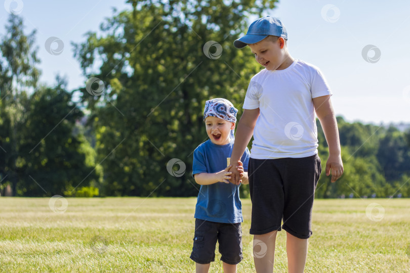 Скачать Веселые дети, два брата, улыбаются от радости. мы с удовольствием гуляем и играем на лужайке в теплую солнечную погоду в парке. эмоции детей на лице. фотосток Ozero