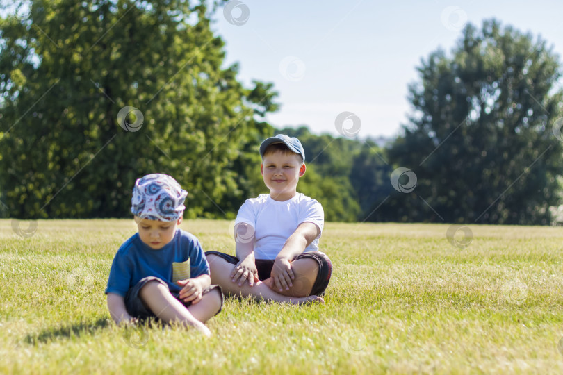 Скачать Веселые дети, два брата, улыбаются от радости. мы с удовольствием гуляем и играем на лужайке в теплую солнечную погоду в парке. эмоции детей на лице. фотосток Ozero