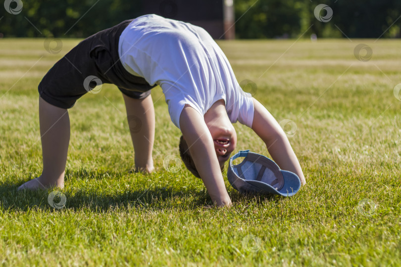 Скачать Жизнерадостный ребенок радостно улыбается. Я с удовольствием гуляю и играю на лужайке в теплую солнечную погоду в парке. эмоции детей на лице. фотосток Ozero