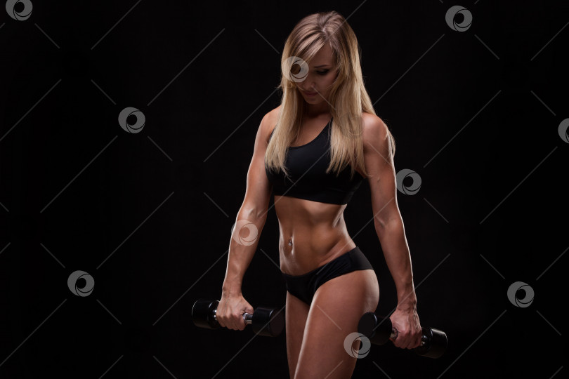 Скачать Красивая спортивная женщина, накачивающая мышцы гантелями, изолированная на темном фоне с помощью copyspace фотосток Ozero