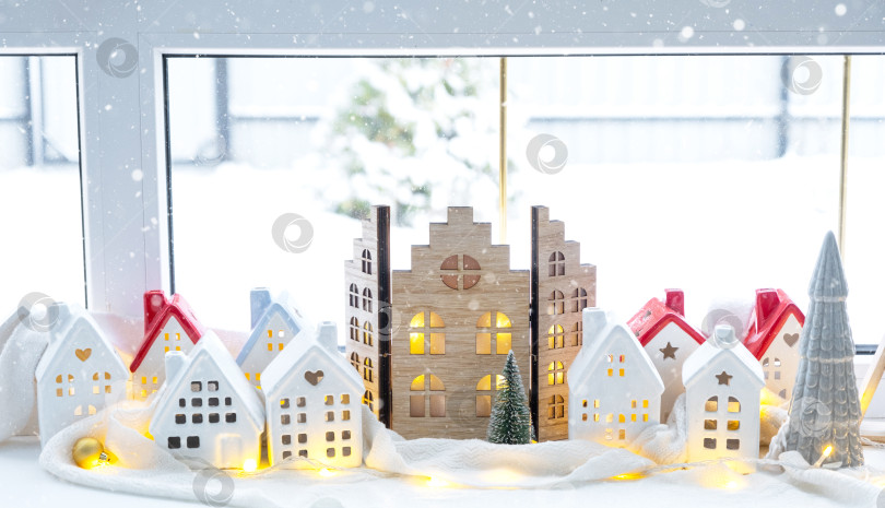 Скачать Уютный рождественский декор крошечного домика небольшого размера на подоконнике со снегом за окном. Подарок на Новый год. Страхование, переезд в новый дом, ипотека, аренда и покупка недвижимости фотосток Ozero