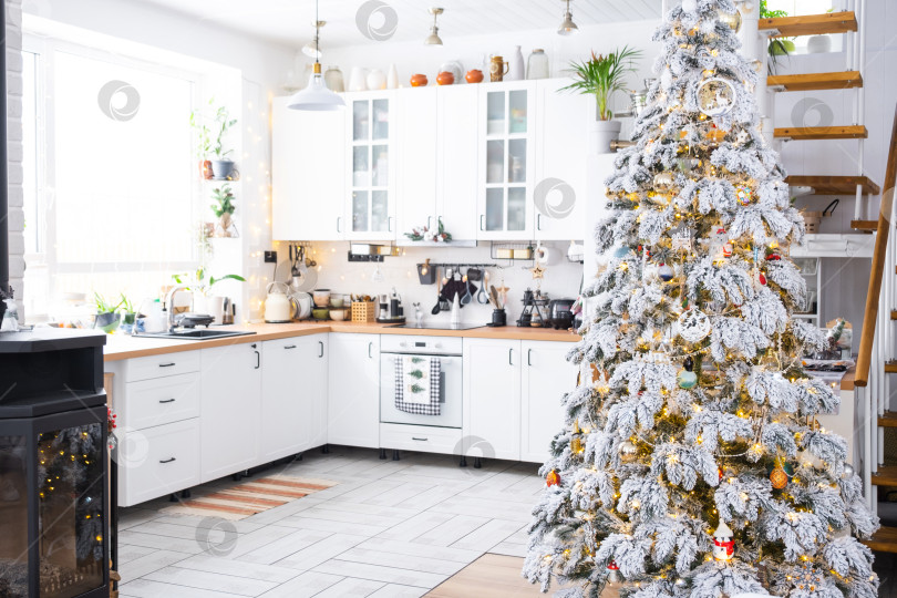Скачать Праздничный рождественский декор на белой кухне, современный деревенский интерьер со снежной елкой и гирляндами. Новый год, рождественское настроение, уютный дом. Общий план фотосток Ozero