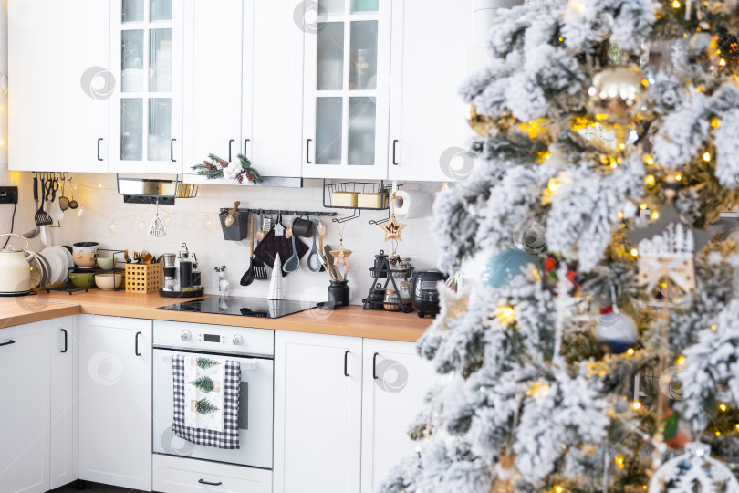 Скачать Праздничный рождественский декор на белой кухне, современный деревенский интерьер со снежной елкой и гирляндами. Новый год, рождественское настроение, уютный дом. Общий план фотосток Ozero