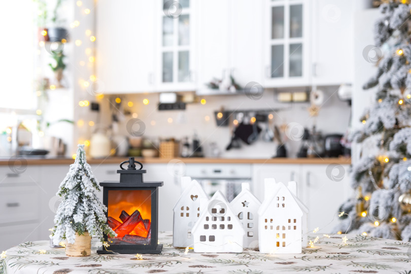Скачать Уютный рождественский декор крошечного домика небольшого размера на столе праздничной белой современной кухни. Подарок на Новый год. Страхование, переезд в новый дом, ипотека, аренда и покупка недвижимости фотосток Ozero