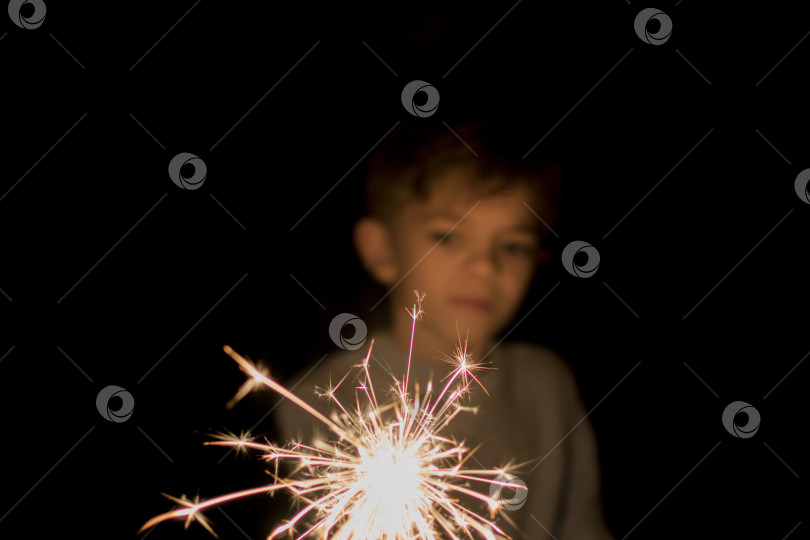 Скачать Маленький мальчик держит зажженный бенгальский огонь фотосток Ozero