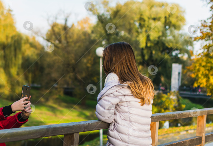 Скачать Друг фотографирует молодую девушку в парке фотосток Ozero