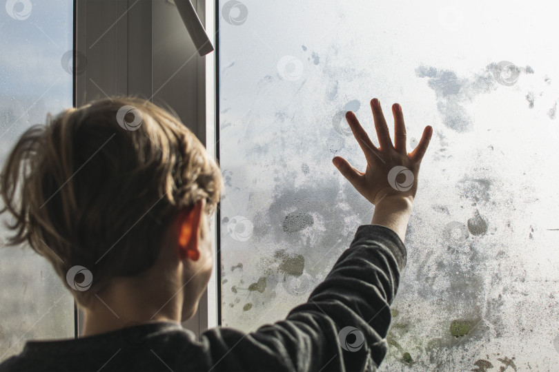 Скачать Маленький мальчик рисует на запотевшем, мокром окне фотосток Ozero
