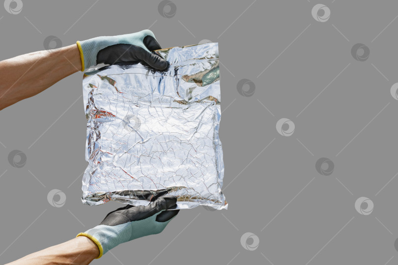 Скачать Рабочий держит в руках упаковочный пакет, изготовленный из материала с фольгой фотосток Ozero