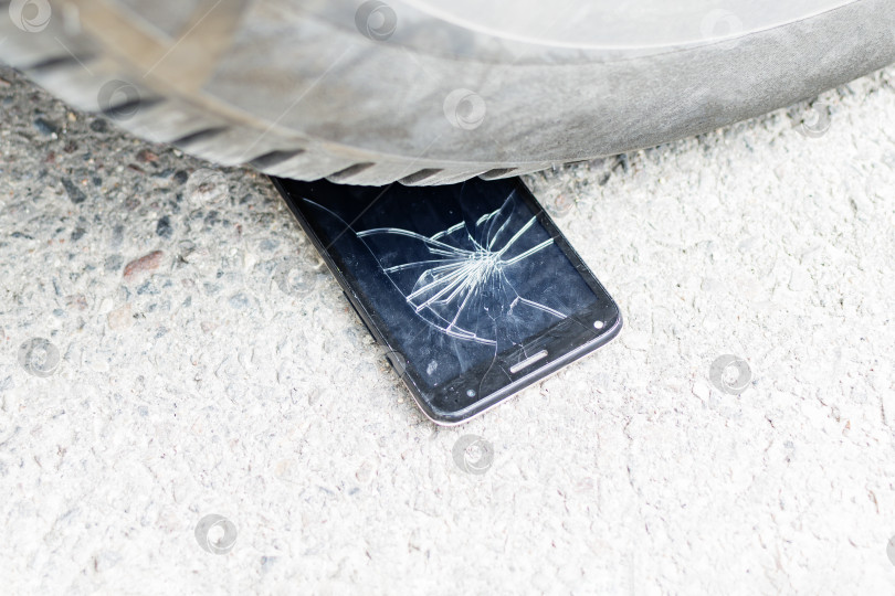 Скачать Сломанный телефон лежит под колесами автомобиля фотосток Ozero