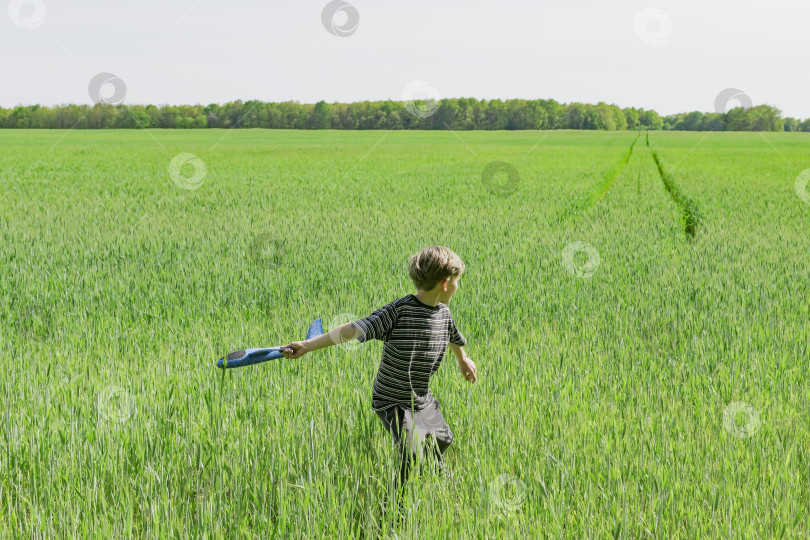 Скачать Маленький мальчик играет в поле, запускает игрушечный самолетик фотосток Ozero