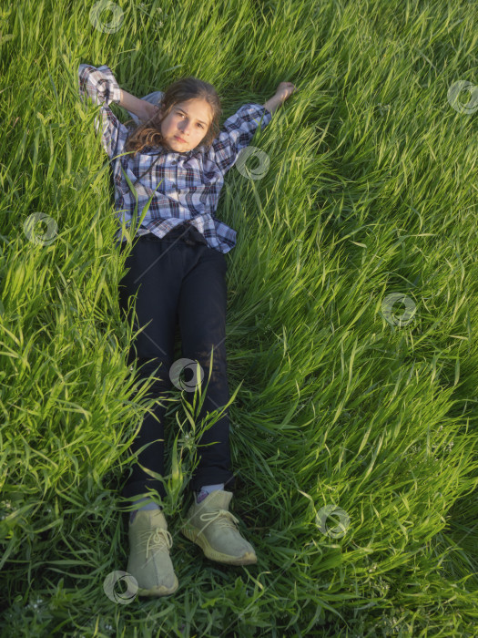Скачать Красивая молодая девушка лежит на зеленой траве под солнцем. Счастливая девушка наслаждается жизнью на пышной лужайке и смотрит в небо. фотосток Ozero