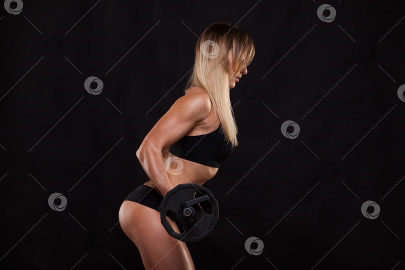 Скачать Красивая фитнес-женщина поднимает штангу. Спортивная девушка, демонстрирующая свое хорошо тренированное тело. изолированный на темном фоне с помощью copyspace фотосток Ozero