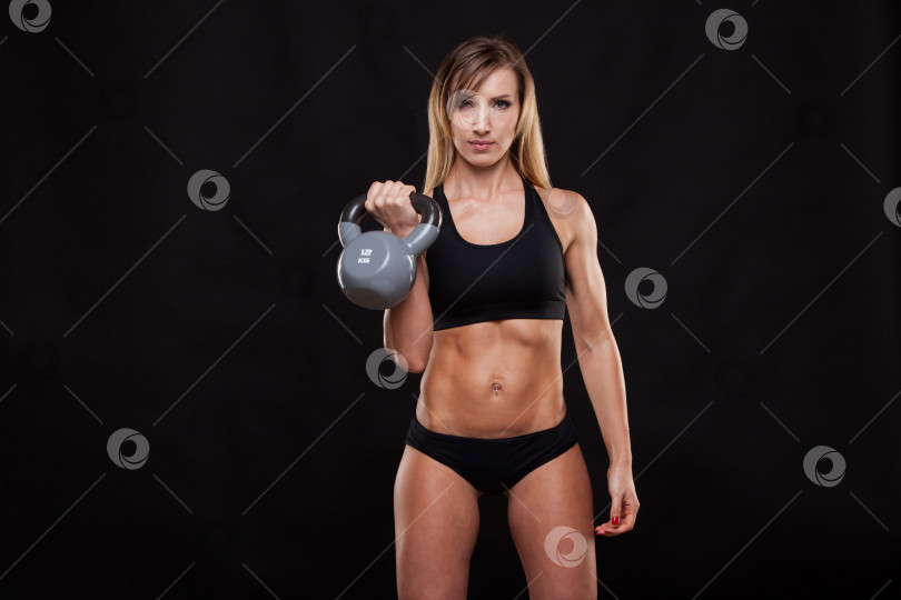 Скачать Молодая привлекательная фитнес-женщина делает упражнение с гирями. Спортивная девушка, демонстрирующая свое хорошо тренированное тело. изолированный на темном фоне с помощью copyspace фотосток Ozero