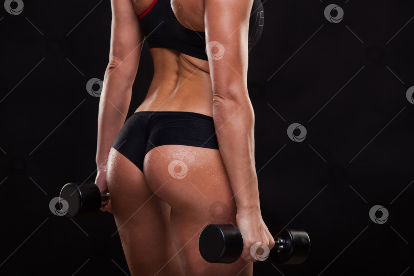 Скачать Попа привлекательной спортивной женщины, держащей гантели, вид сзади, изолированный на темном фоне с copyspace фотосток Ozero